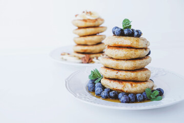 Stack of homemade small thick pancakes served with fresh blueberries.