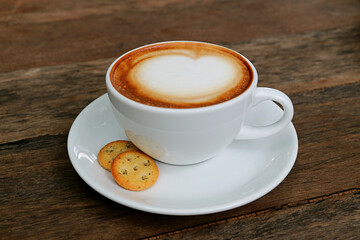 Closeup a cup of cappuccino coffee with a pair of crackers isolated on wooden table