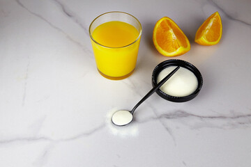 Collagen protein powder and a glass of orange juice on light background. Dietary supplement for skin and joints.