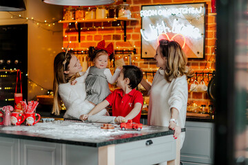 Woman and kids posing in the kitchen against Christmas background. Happiness.