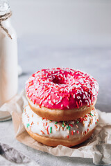 Bright pink donuts and a bottle of milk on the table close up, vertical photo