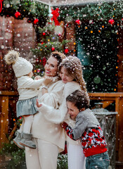 Woman and kids in sweaters posing in the back yard. Snowing.