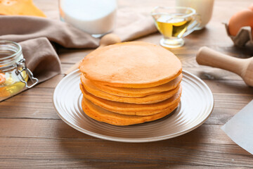 Tasty pumpkin pancakes on table