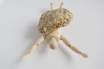 石に押しつぶされるデッサン人形
