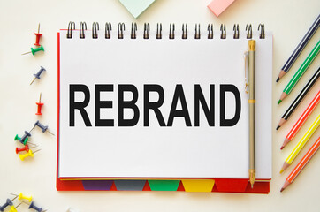  the word rebrand is written on a notebook with pencils