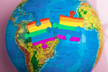 LGBT as a part of society - one puzzle with the coloring of the flag of sexual minorities on a blue globe background