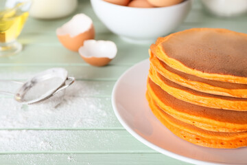 Tasty pumpkin pancakes on table