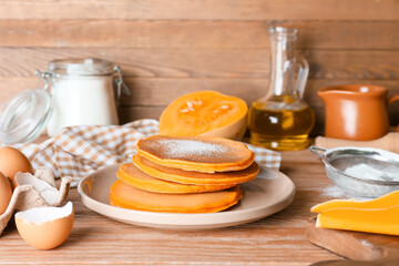 Tasty pumpkin pancakes with ingredients on table