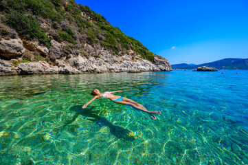 Girl with sun hat relaxing and swimming at Porto Timoni beach at Afionas is a paradise double beach...