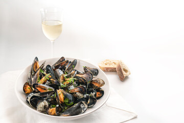 Mussels with herbs, bread and wine on a white table, generous copy space