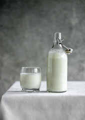 Kefir in a bottle and in a glass on a white table
