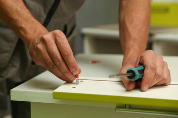 worker assembles furniture in the kitchen. furniture assembly service concept