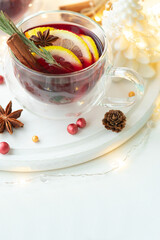 Christmas mulled red wine with spices and citrus on white wooden table. Traditional hot drink at Christmas