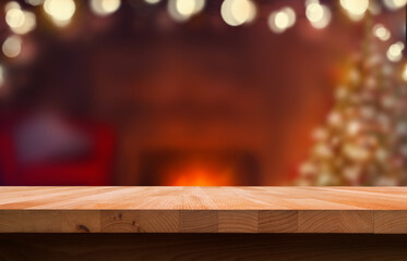 A Christmas wood tabletop product display with a festive background of a Christmas tree and open fire and an empty space on the table.