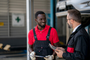 The mechanic discuss with his chief during car damage inspection at the garage 