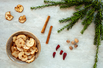 Dried healthy homemade fruit snacks in ceramic bowl with winter spices: nutmeg cinnamon and chili. Winter time flat lay decoration.