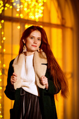 red-haired girl in the winter evening on the street against the background of Christmas lights