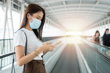 Portrait of a young woman in a medical mask for anti-coronavirus COVID-19 pandemic infectious disease outbreak protection and use a smartphone in Public area. Concept of Virus pandemic and pollution