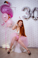 birthday of a girl in a pink dress with balloons and a cake 30 years old