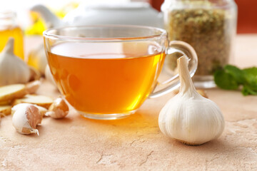 Cup of healthy garlic tea on color background