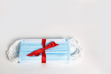 Medical mask as gift with a red ribbon  on white background, COVID 19 protection ,The concept of health care in the Happy new year Festival