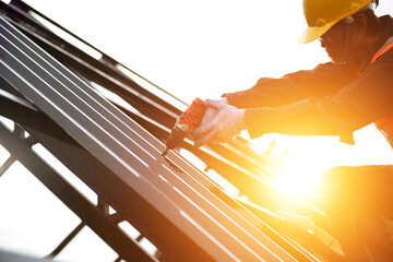 Asian construction workers wear safety straps while working on the roof structure of the building...