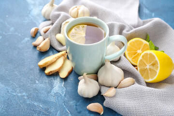 Cup of healthy garlic tea on color background