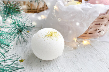 Wintertime spa concept with bath bomb, fir tree branch over ligths. Festive aromatherapy pampering....