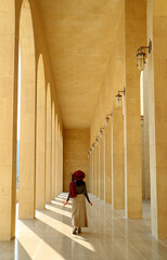 Fototapeta premium Female visitor walking along the marble corridor of the Al Fateh Grand Mosque