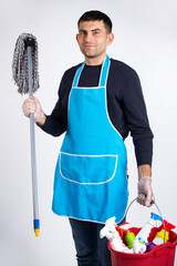 Gender stereotypes, a man in gloves, vabre and chemicals for cleaning the house. Photo on a white...