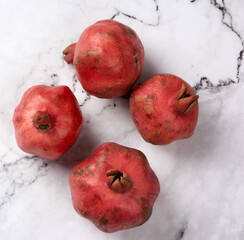 ripe red pomegranates on a white marble table