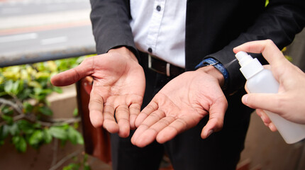 Close Up Of Businessman Having Hands Sprayed With Sanitiser During Health Pandemic
