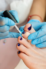 Process pedicure close up. Unrecognizable people. Master chiropody applying gel nail polish. Spa....