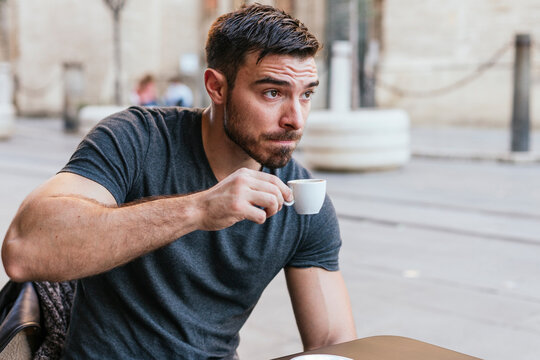 White man sitting in a cafeteria drinking coffee
