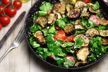 Selective focus. Warm salad with spinach and eggplant in a frying pan. Healthly food. Vegan lunch idea.