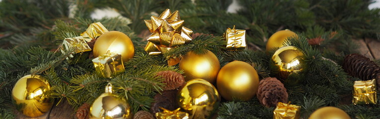 Christmas decorations yellow balls, fir branches on a wooden background with copy space. Gold style Christmas card.