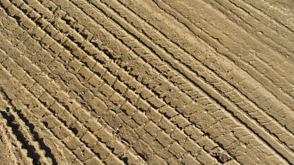 Muddy road with tyre tracks different tread patterns. Muddy wet track near a farm