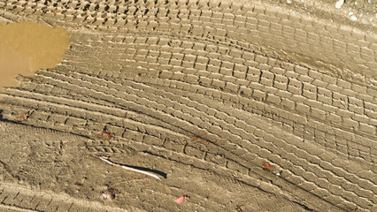 Fototapeta premium Muddy road with tyre tracks different tread patterns. Muddy wet track near a farm