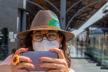 Closeup of a girl with a protective mask looking at a phone - new normal