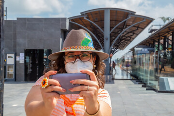 Closeup of a girl with a protective mask looking at a phone - new normal