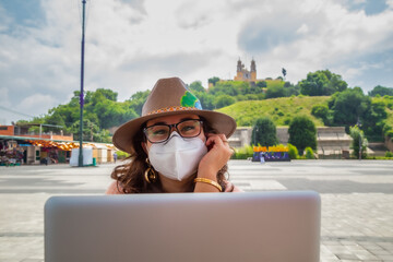 Closeup of a girl with a protective mask working on a laptop - new normal