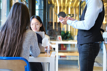 Caucasian waiter taking clients order in a restaurant during coronavirus outbreak. New normal in restaurants. Coronavirus pandemic.