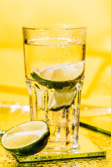 sliced lime in glass with rum on yellow