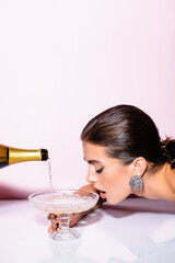 brunette woman drinking champagne from glass near bottle on white © LIGHTFIELD STUDIOS
