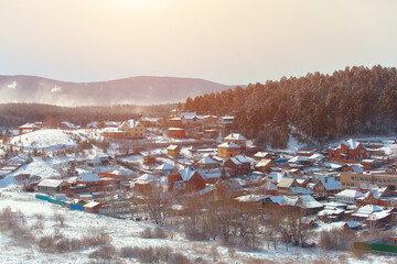 Russian village winter. Roofs covered with snow, a Blizzard sweeps in the forest