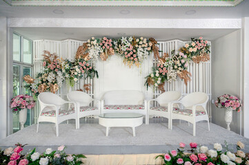 White theme of wedding stage decoration with colorful flowers and chair for guest in asian traditional