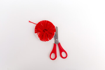 making red pompons from thread, top view, white background, handmade craft