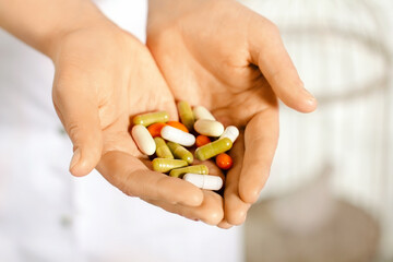 woman in white coat holding a handful of pills in palms