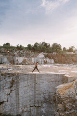 Yoga girl in black suit doing yoga exercises at sunset in a marble quarry