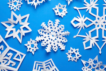 Composition with handmade paper snowflakes on blue background